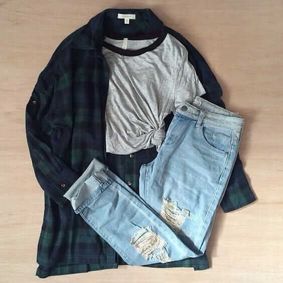 Grunge outfit idea nº21: Dark green and blue flannel shirt, short sleeve varsity T, and ripped light blue jeans