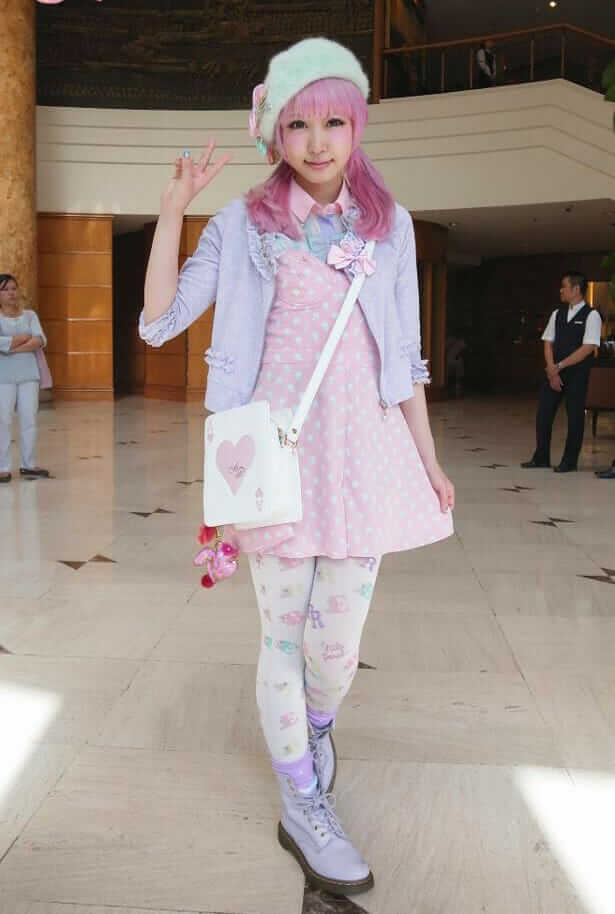 Kawaii Fairy Kei Aesthetic Outfit Idea: A Printed Baby Pink Dress, with a Lavender Cardigan, Printed Pastel Blue Tights, Baby Purple Combat Boots, and an Ace of Hearts Shoulder Bag