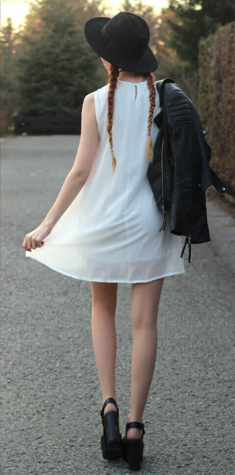 White lace dress, black faux-leather jacket, black platform sandals, black wide brimmed hat, and a choker, from the back