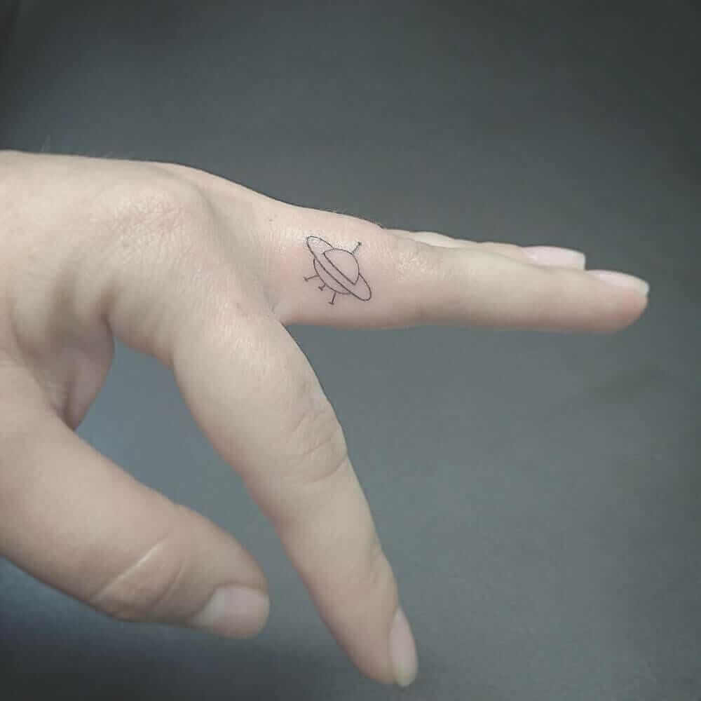 Small UFO tattoo on the left middle finger