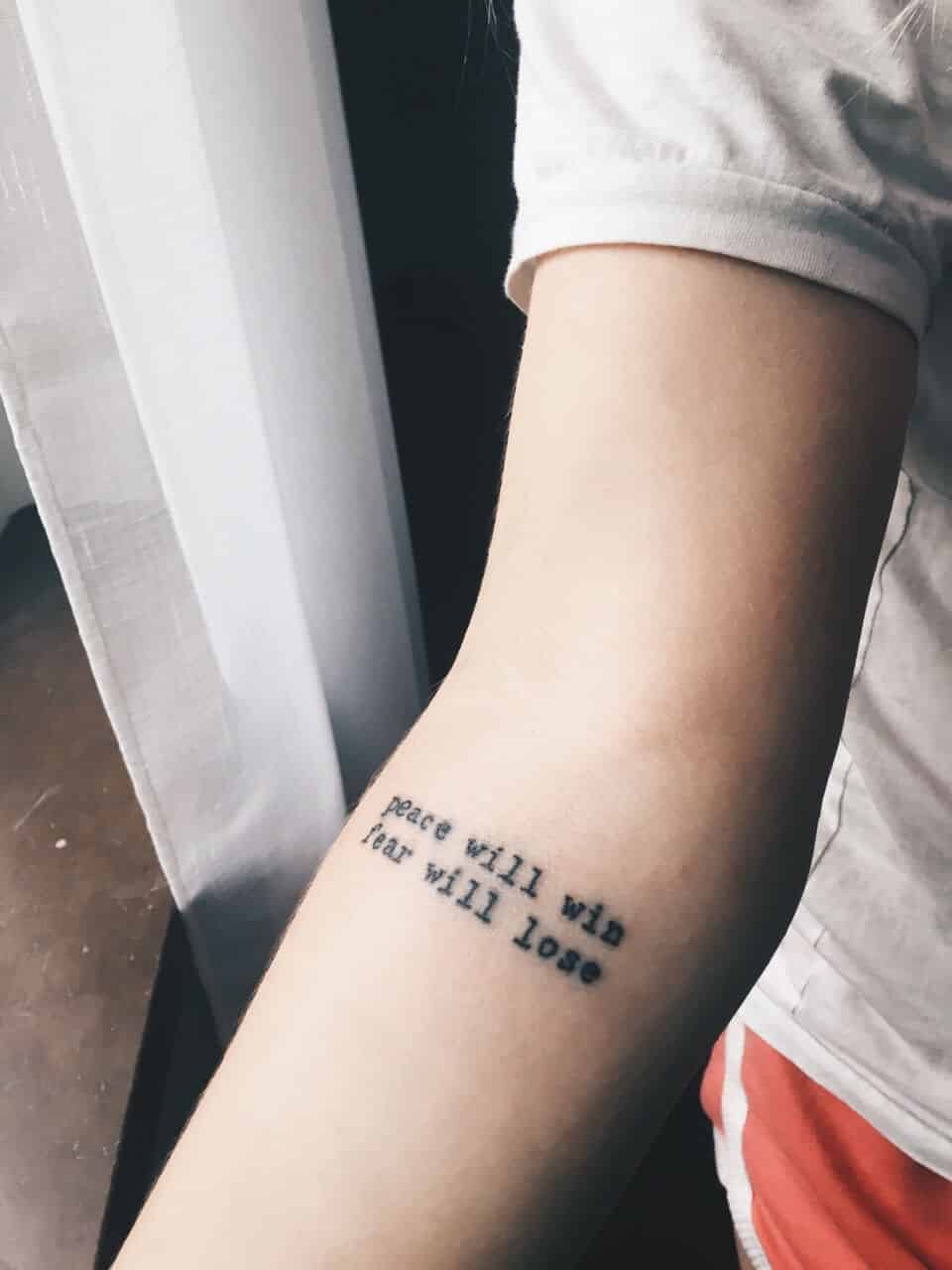 "Peace will win. Fear will lose" arm tattoo quote