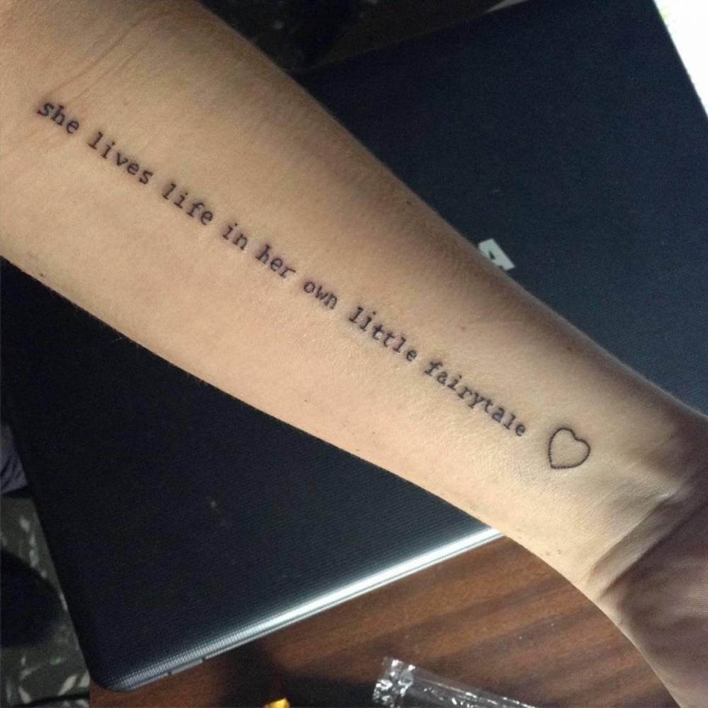 "she lives life in her own little fairytale" arm quote tattoo