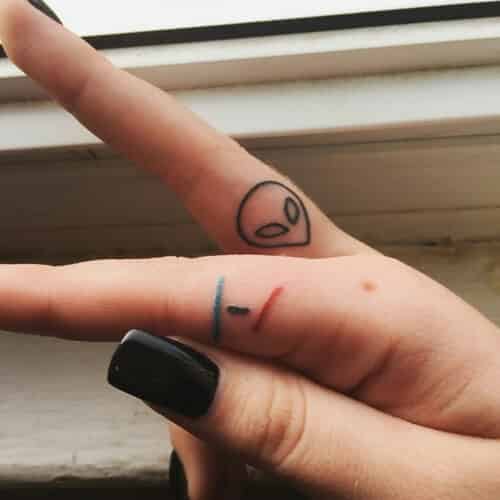 Small alien head finger tattoo